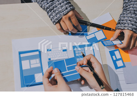 Group of young application developers analyzing uxui mobile app templates during a working meeting 127815468