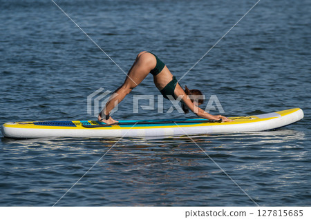 Caucasian woman doing yoga on a SUP board. Caucasian woman doing yoga on a SUP board. 127815685