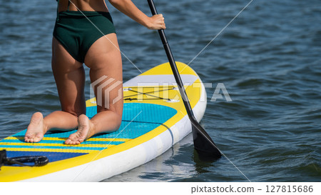 Caucasian woman riding a SUP board on the lake. Summer sport. Caucasian woman riding a SUP board on the lake. Summer sport. 127815686