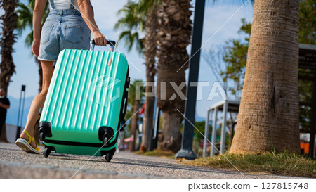 A Caucasian woman walks with a suitcase to the coast. 127815748