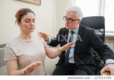 Elderly male hypnotherapist with a female patient. An alternative way to heal mental health Elderly male hypnotherapist with a female patient. An alternative way to heal mental health 127815769