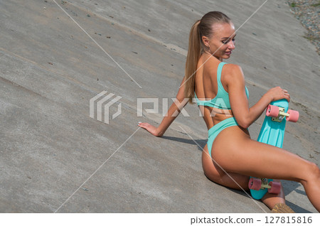 Caucasian woman in a swimsuit with a penny board.  127815816