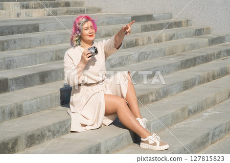 Caucasian woman with curly colored hair takes pictures on an old retro camera outdoors Caucasian woman with curly colored hair takes pictures on an old retro camera outdoors 127815823