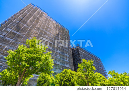 Yokohama cityscape in Japan. Apartment building repairs and inspections, scaffolding and protective nets. Satellite antennas outside the nets... 127815934