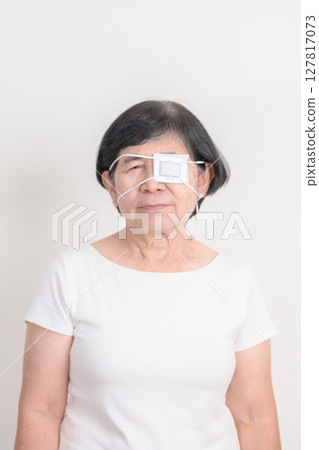 Elderly Woman with Eye protecting by Eye Pad for concepts of Eye disease, Cataract, Glaucoma, Age Related Macular Degeneration, Diabetic Retinopathy, Vitreous, Conjunctivitis, World Glaucoma day 127817073