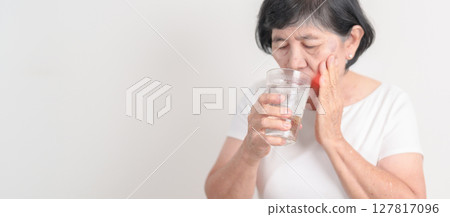 Elderly woman having toothache and pain after drink ice water for concept of Teeth Sensitive to Cold, Tooth Decay and Gum Disease, Grinding Teeth and Stress, Exposed Nerve Roots, Crack and Receding Elderly woman having toothache and pain after drink ice water for concept of Teeth Sensitive to Cold, Tooth Decay and Gum Disease, Grinding Teeth and Stress, Exposed Nerve Roots, Crack and Receding 127817096
