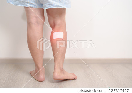 Elderly woman having Calf pain with Medicated pain relief patch plaster for concepts of Calf Muscle Strain, muscle pull, Leg Cramp, Sprain, aches, Varicose Veins, Deep Vein and world Thrombosis day 127817427