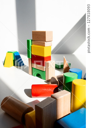 Colorful wooden blocks tower in sunlit room with shadows 127818093