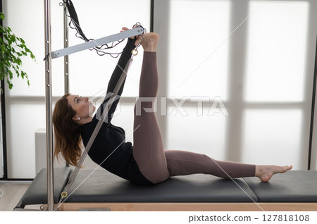 Woman doing Pilates on reformer. Woman doing Pilates on reformer. 127818108