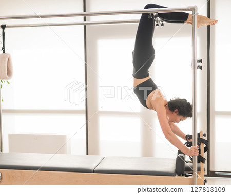 Asian woman doing pilates on reformer.  127818109