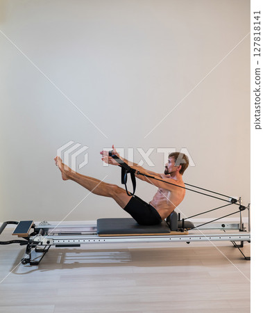 A man doing Pilates on a reformer. A man doing Pilates on a reformer. 127818141