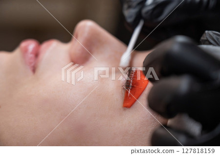 Caucasian woman undergoing eyelash lamination procedure.  127818159