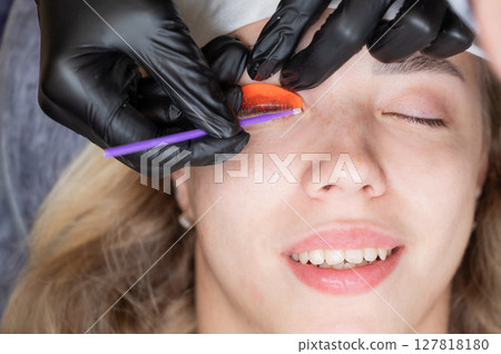 Caucasian woman undergoing eyelash lamination procedure.  127818180