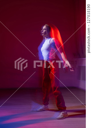 A young woman dances contemporary dances in blue and red light. Long exposure. Vertical photo.  127818190