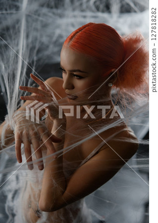 Red-haired woman entangled in a net trap amid a dramatic backdrop 127818282