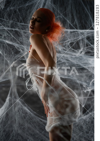Woman in captivating red attire entangled in a net trap of delicate webs 127818283