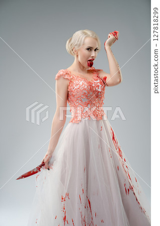 Bride in a blood-soaked dress posing dramatically in a studio setting Bride in a blood-soaked dress posing dramatically in a studio setting 127818299