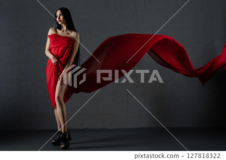 Elegant woman draped in flowing red fabric accentuates beauty and allure Elegant woman draped in flowing red fabric accentuates beauty and allure 127818322
