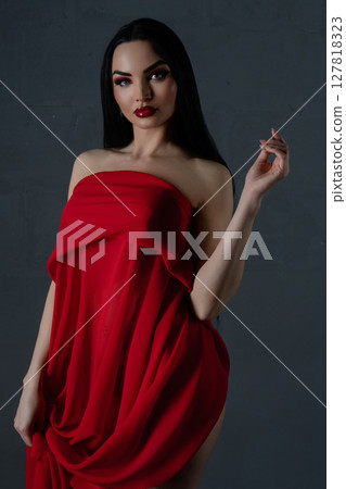 Elegant woman in striking red lingerie draped with fine fabric 127818323