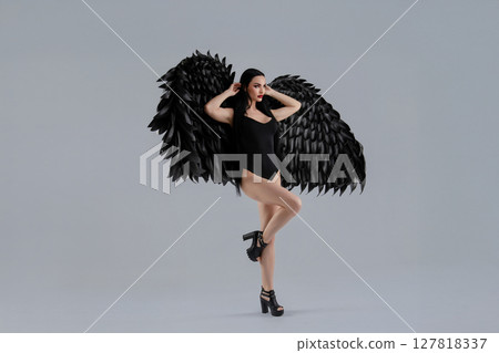 Woman in lingerie poses gracefully with elaborate black wings 127818337