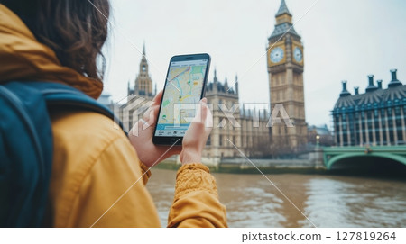 Tourist using a navigation app on a tablet while enjoying the view of big ben and the houses of parliament in london, england, on a cloudy day, capturing the essence of urban travel 127819264