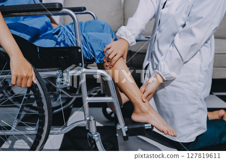 Physiotherapist checking knee of female patient stock 127819611
