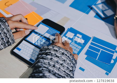 Group of young application developers analyzing uxui mobile app templates during a working meeting 127819638