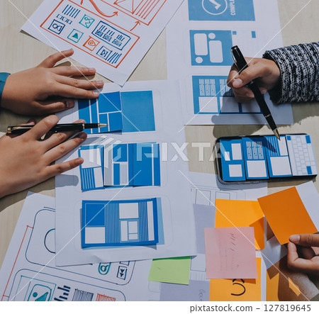 Group of young application developers analyzing uxui mobile app templates during a working meeting 127819645