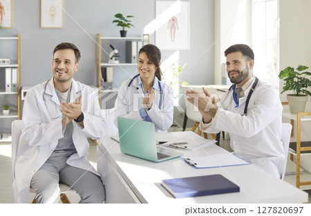 Happy smiling doctors rejoicing at success in treatment applauding sitting in clinic Happy smiling doctors rejoicing at success in treatment applauding sitting in clinic 127820697