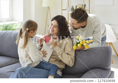 Cute small daughter, child girl and loving smiling young mother, father congratulating  127820699