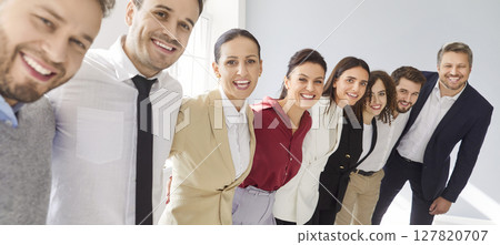 Group portrait of a happy smiling business people standing in a row and hugging on gray background. 127820707