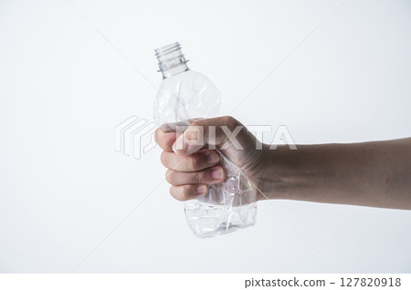 A man's hand crushing an empty plastic bottle 127820918