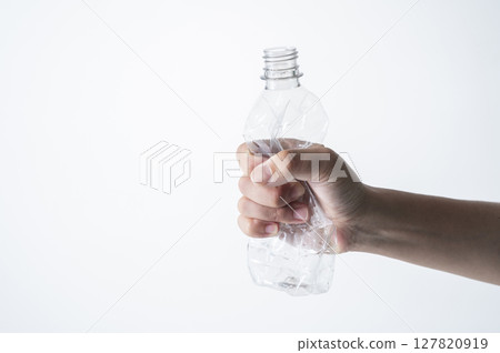 A man's hand crushing an empty plastic bottle 127820919