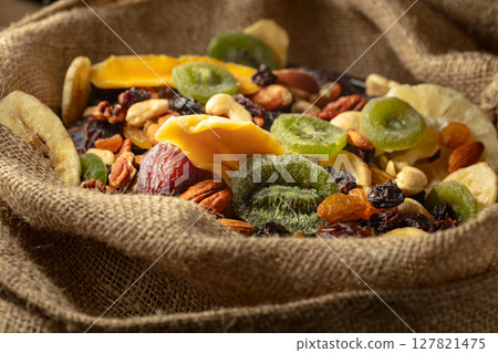 Dried tropical fruits and nuts in burlap bag. Dried tropical fruits and nuts in burlap bag. 127821475