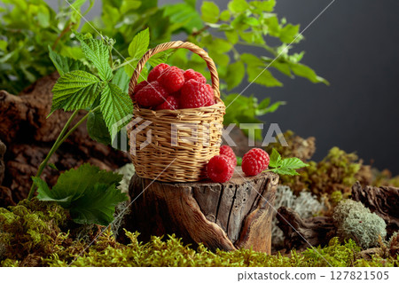 Small wicker basket filled with fresh, ripe raspberries. 127821505