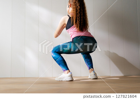 Woman in fashionable sportswear is doing exercise. 127821604