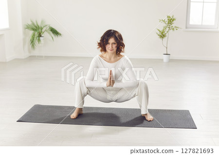 Sporty attractive woman practicing yoga, sitting in Malasana exercise, Garland pose, working out Sporty attractive woman practicing yoga, sitting in Malasana exercise, Garland pose, working out 127821693