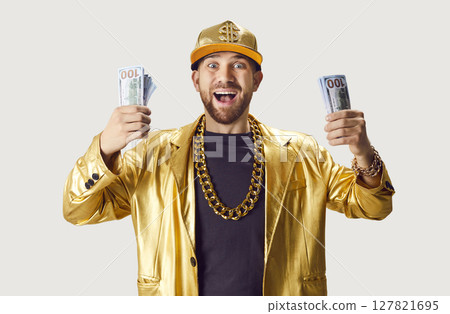 Funny young man in golden suit holding money cash on white studio background. 127821695
