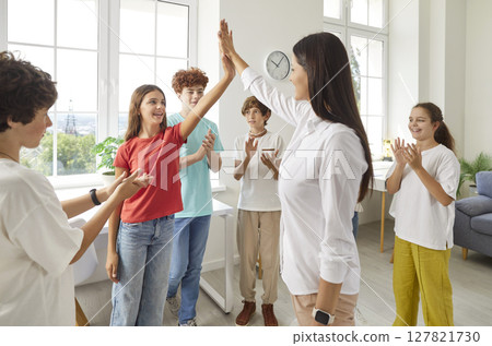 Joyful preteens celebrating success with their friendly teacher, giving high five and applauding. Joyful preteens celebrating success with their friendly teacher, giving high five and applauding. 127821730