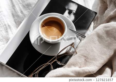 Espresso Cup on Portrait Book with Spoon and Glasses in Minimalist European Cafe Setting 127821857