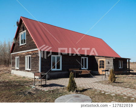 A Beautiful Rustic Wooden House with a Bright Red Roof Set in Open, Vast Landscape A Beautiful Rustic Wooden House with a Bright Red Roof Set in Open, Vast Landscape 127822019