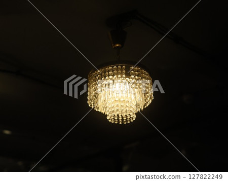 An Elegant Crystal Chandelier Beautifully Illuminating a Dark Room with Subtle Warmth and Style An Elegant Crystal Chandelier Beautifully Illuminating a Dark Room with Subtle Warmth and Style 127822249