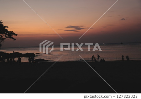 A Serene and Beautiful Sunset at the Beach with Stunning Silhouettes of People Gathered A Serene and Beautiful Sunset at the Beach with Stunning Silhouettes of People Gathered 127822322