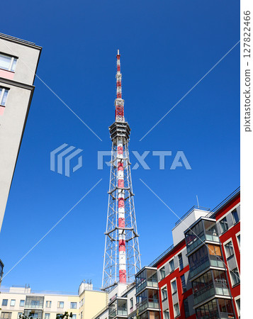 A striking Urban Communication Tower stands tall against a clear blue sky during daylight hours 127822466