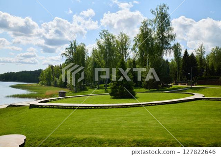 Enjoy a serene lakeside park with lush greenery and a scenic walkway for relaxation Enjoy a serene lakeside park with lush greenery and a scenic walkway for relaxation 127822646