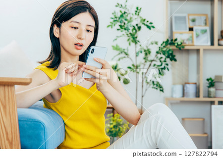一個女人在客廳裡看著她的智能手機 127822794