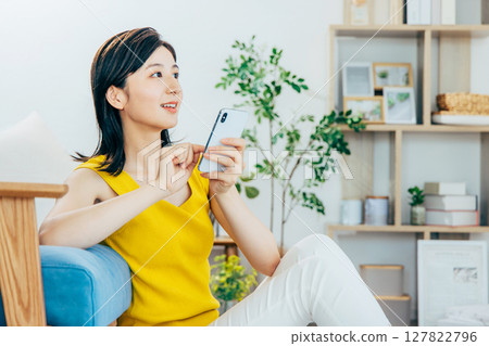 一個女人在客廳裡看著她的智能手機 127822796