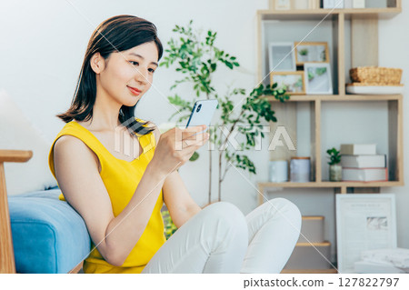 一個女人在客廳裡看著她的智能手機 127822797