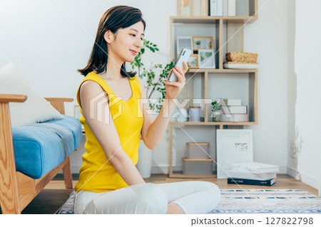 一個女人在客廳裡看著她的智能手機 127822798