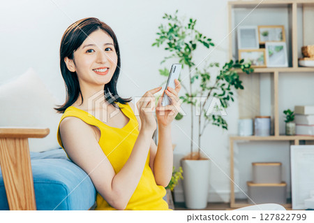 一個女人在客廳裡看著她的智能手機 127822799
